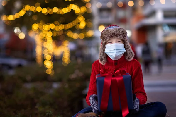 Cheerful Boy Wearing Mask Holding Christmas Present Enjoying Outdoor Holiday Imagen De Stock