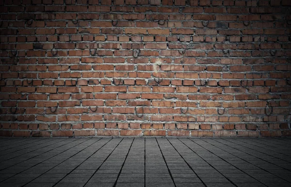 Empty room with bricks wall and tiled floor. Dark background.