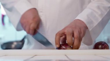 Aşçı soğanı doğrama tahtasındaki keskin bıçakla kesiyor..