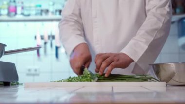 Şef kesme tahtasındaki keskin bıçakla taze soğan kesiyor..
