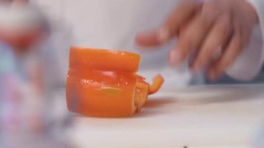 Şef kesme tahtasında keskin bir bıçakla dolma biber kesiyor..