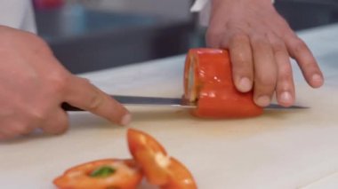 Şef kesme tahtasında keskin bir bıçakla dolma biber kesiyor..