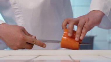 Şef kesme tahtasında keskin bir bıçakla dolma biber kesiyor..