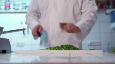 Şef kesme tahtasındaki keskin bıçakla taze soğan kesiyor..