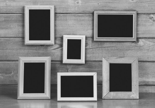 Old photo frames on the wooden wall and table, gray background