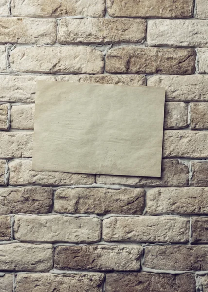 Old paper on brick wall — Stock Photo, Image
