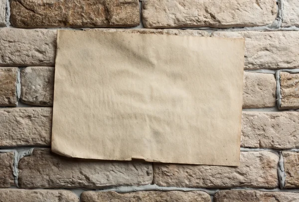 Old paper on brick wall — Stock Photo, Image