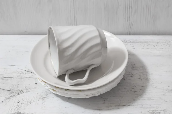 Стопка белых тарелок и чашки на столе — стоковое фото