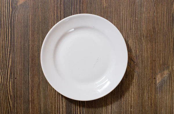 Plate on brown wooden table — Stock Photo, Image