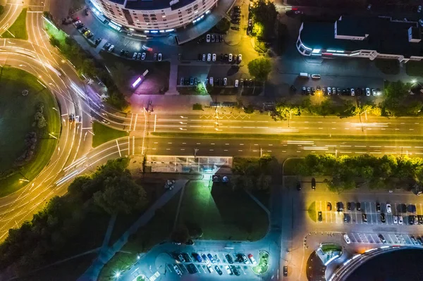 roundabout intersection and city street. road traffic with car light trails. aerial top view at night.