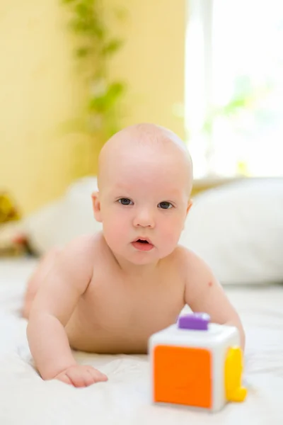 Ребенок играет с игрушкой на кровати — стоковое фото