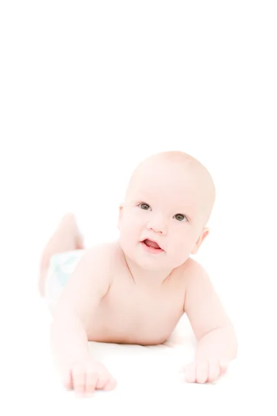 Pequeño bebé divertido acostado en la cama blanca sobre fondo blanco — Foto de Stock