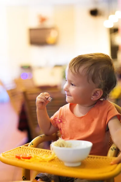 Linda niña comiendo espaguetis en un restaurante pequeño — Foto de Stock
