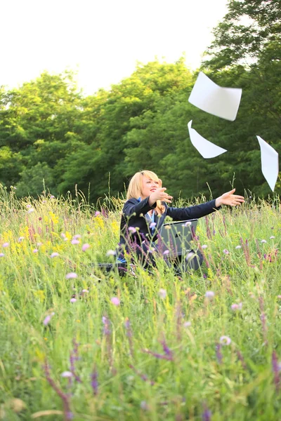 Businesswoman on nature with laptop catch documents — Stock Photo, Image