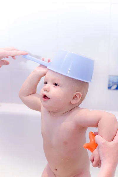 Baby in Badewanne mit Spielzeug wie eine Mütze auf den Kopf gestellt — Stockfoto