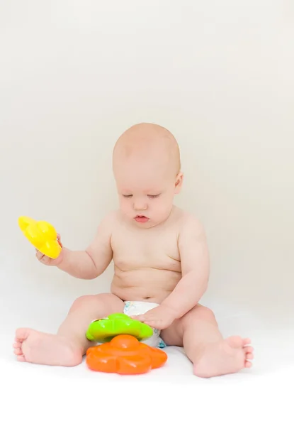 Pequeño bebé jugando con juguetes sobre fondo gris claro —  Fotos de Stock