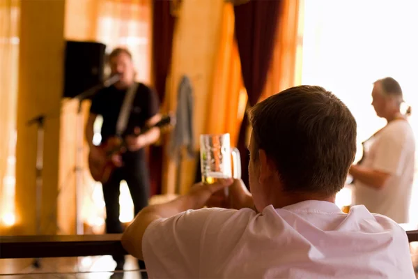 Мужчина пьет пиво и играет в группе. — стоковое фото
