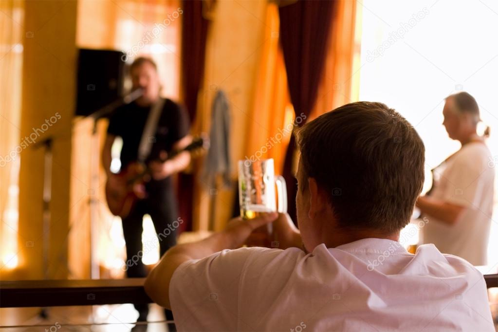 Man having beer and  look on playing band