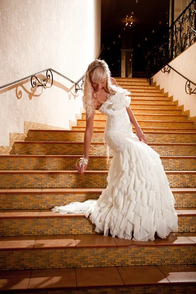 Vacker flicka i en bröllopsklänning går ner för trappan — Stockfoto