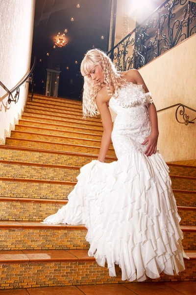 Schöne Mädchen in einem Hochzeitskleid die Treppe hinunter — Stockfoto