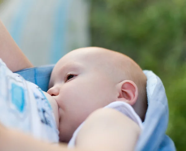 Mother breast feeding her infant in sling — Stock Photo, Image