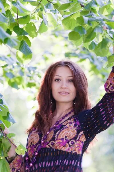 Happy young woman under green tree in spring park — Stock Photo, Image