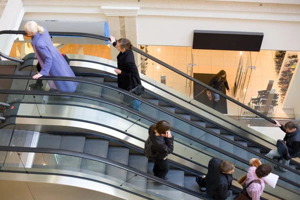 Pessoas em escadas rolantes num centro comercial. Desfoque de movimento — Fotografia de Stock