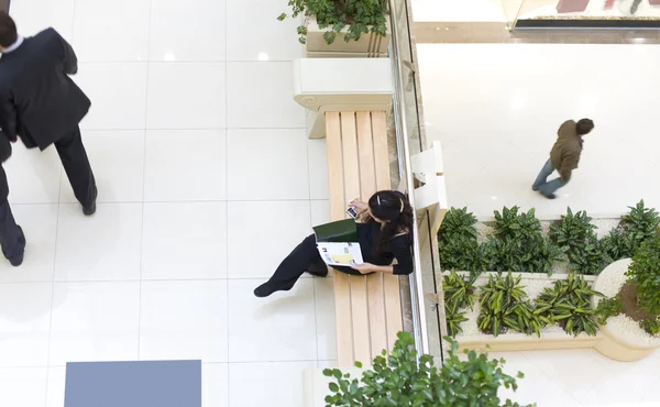 Chica sentada en un banco en un centro comercial — Foto de Stock