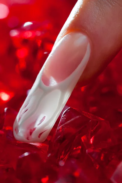 Dedo com bela manicure tocar um cristal vermelho — Fotografia de Stock