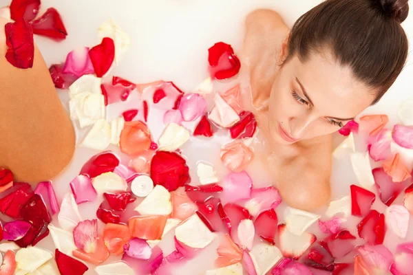 Attraktiva naken tjej har ett bad med mjölk och rosenblad — Stockfoto