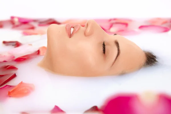 Attractive girl takes a bath with milk and rose petals — Stock Photo, Image