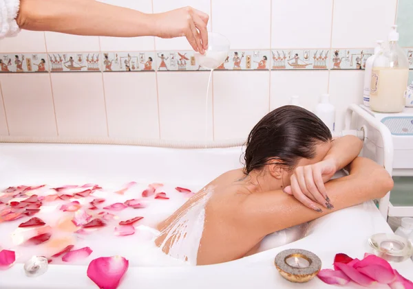 Attractive naked girl enjoys a bath with milk and rose petals — Stock Photo, Image