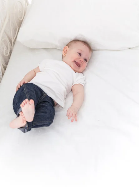 Grappige kleine babymeisje op witte bed — Stockfoto