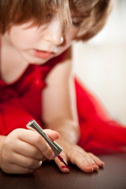 Kırmızı elbiseli küçük kız çivi oje ile boyalı