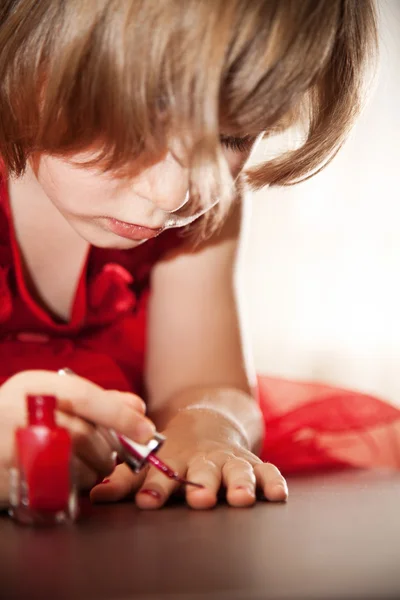 Kleines Mädchen im roten Kleid lackierte Nägel mit Nagellack — Stockfoto