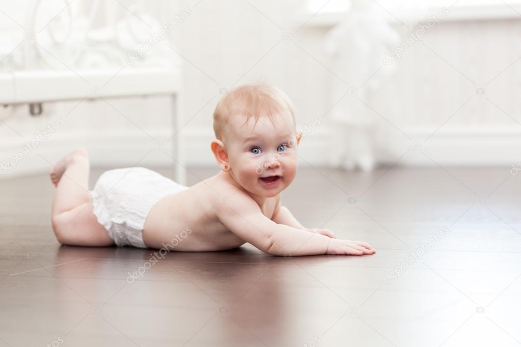 Happy seven month old baby girl crawling on a hardwood floor