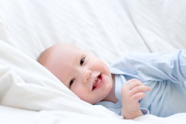 Neşeli bebek beyaz yatakta dinleniyor