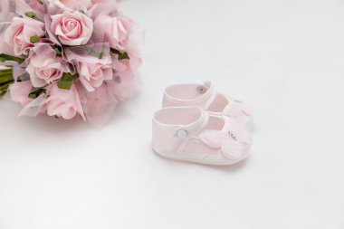 Pembe çiçekler ve beyaz yatakta çocuk sandalet