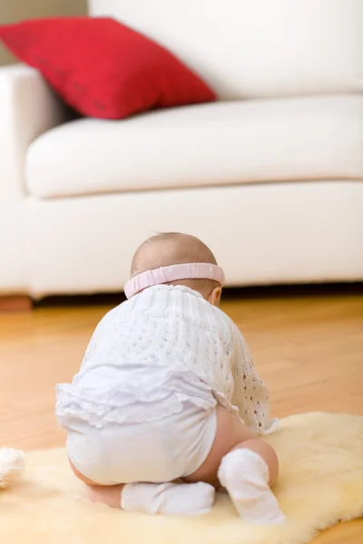 Alone little baby girl sit down on fur at hardwood floor — Stock Photo, Image