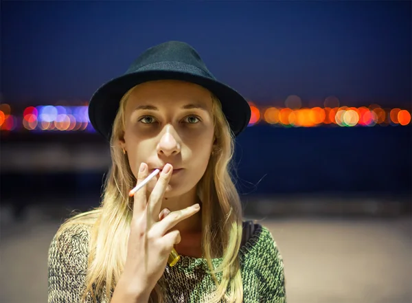 Young girl in a hat smoking a cigarette on the street — Stock Photo, Image