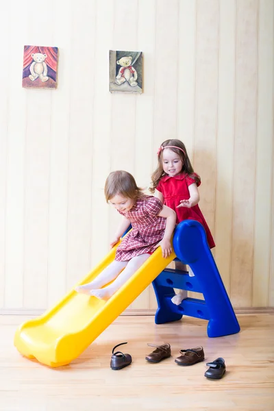 Zwei entzückende Mädchen, die Spaß auf der Spielplatz-Rutsche haben — Stockfoto