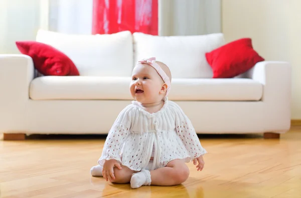 Boldog baba lány ül egy keményfa padló — Stock Fotó