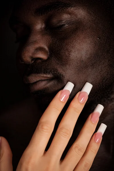 Beyaz kız uzun manikür ile dokunmatik siyah bir adamın yüzü