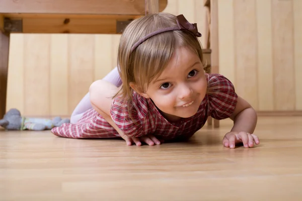 Felice bambina strisciando sul pavimento in legno duro — Foto Stock