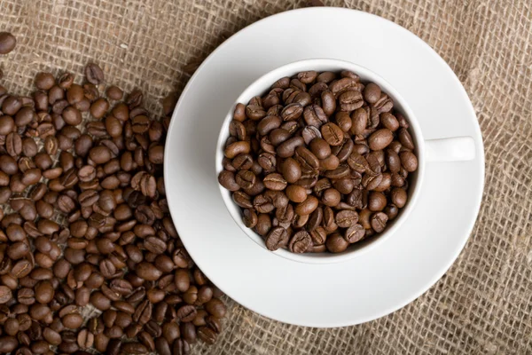 Taza con granos de café recién tostados en tela de saco —  Fotos de Stock