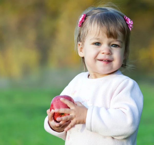 Bambina nel parco con mela rossa in mano — Foto Stock