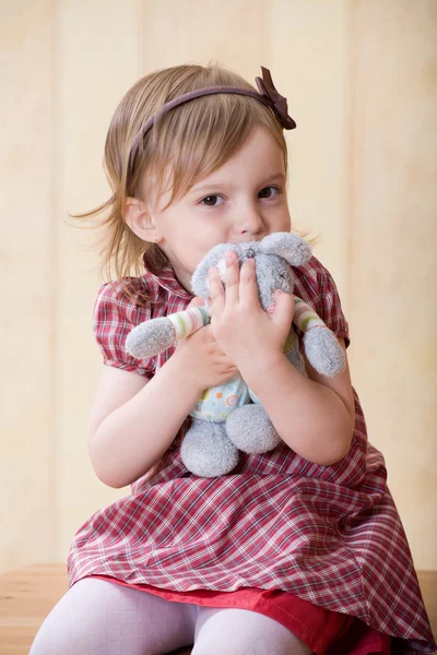 对一个人的怀里的小女孩扣玩具兔子 — 图库照片