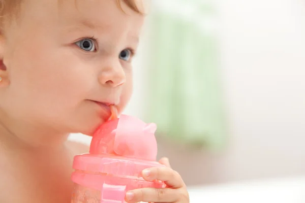 Małe dziecko niebieskooka dziewczyna pije sok z butelki — Zdjęcie stockowe