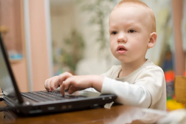 Kleiner Junge tippt zu Hause Text auf Laptop — Stockfoto