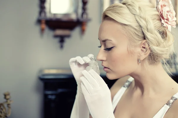 Portret van mooie jonge vrouw een fles parfum ruiken — Stockfoto